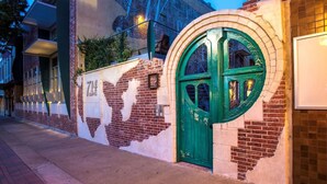 Un edificio con una puerta verde en arco, fachada de ladrillo y un mural en la pared.