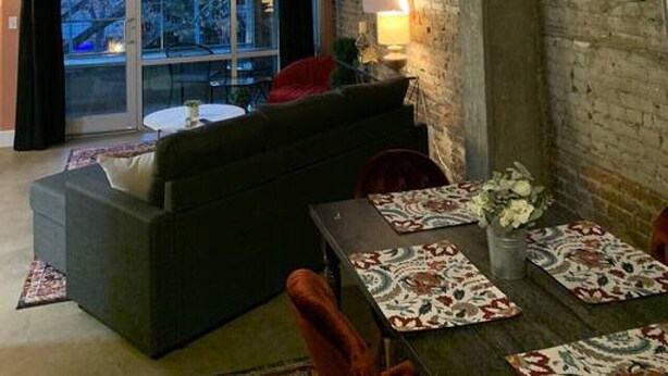 Un interior acogedor con un sofá, una mesa con manteles individuales estampados y una araña.