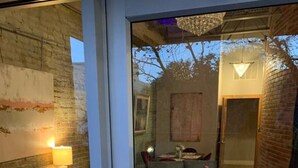Un interior moderno con un cristalero que da a una sala de estar con sofá, mesa de centro y alfombra estampada.