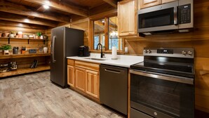Une cuisine moderne avec des meubles en bois, des appareils électroménagers en acier inoxydable et un plancher en bois.