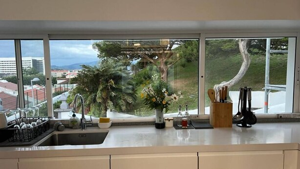 Eine Küche mit einem großen Fenster, einer Spüle und einer Vase mit Blumen.