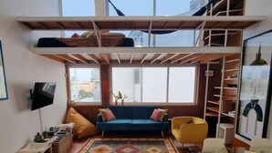 Ein Loft-Wohnzimmer mit blauem Sofa, gelbem Sessel und einem Glastisch.