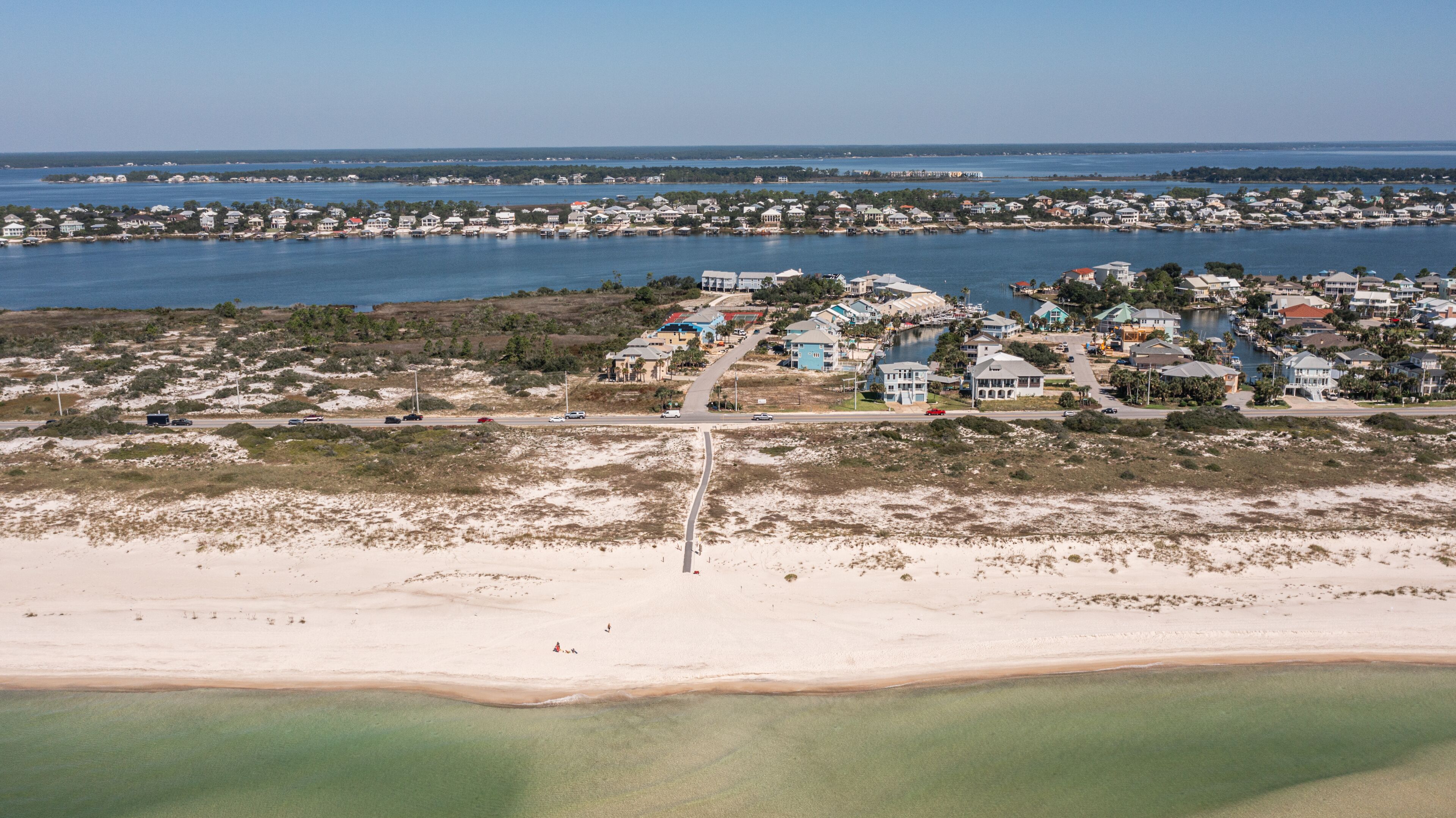 Vista aérea de una zona residencial costera con casas, una playa y un puerto deportivo.