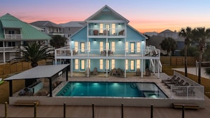 Ein zweistöckiges Haus mit Swimmingpool, Sitzgelegenheit im Freien und einem Balkon.