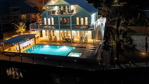 Ein zweistöckiges Gebäude mit Swimmingpool, Sitzgelegenheiten im Freien und einem überdachten Bereich.