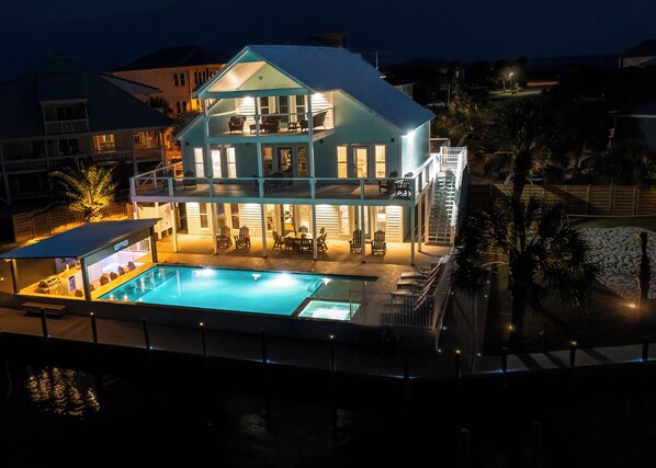 A two-story building with a swimming pool, outdoor seating, and a covered area.