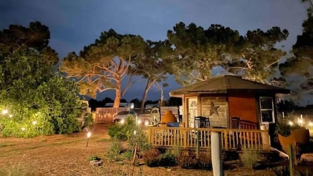 A rustic cabin with a wooden deck, surrounded by trees and a clear night sky. - Stay on the farm - 1 bedroom cottage with deck outside of Davis (Davis)