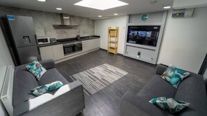 A modern kitchen with a built-in oven, microwave, and a large screen TV mounted on the wall. - Captivating 1-bed Studio in Birmingham (Birmingham)