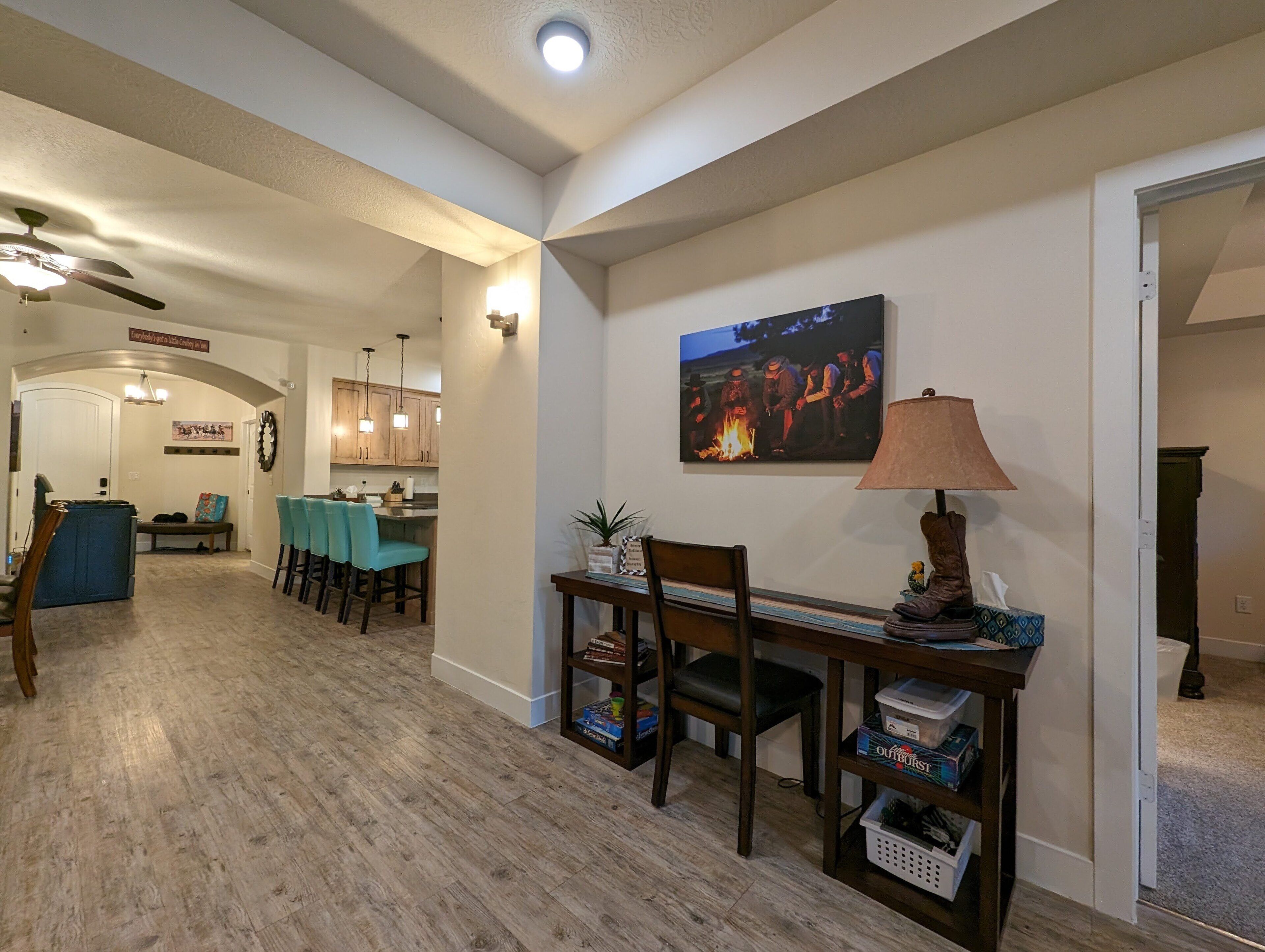 A spacious living area with a dining table, chairs, a lamp, and a painting on the wall.
