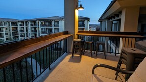 A balcony with a wooden railing, a small table with stools, and a hanging light fixture. - The Hideout is a recently remodeled, fully wheelchair-accessible, luxury condo  (St. George)