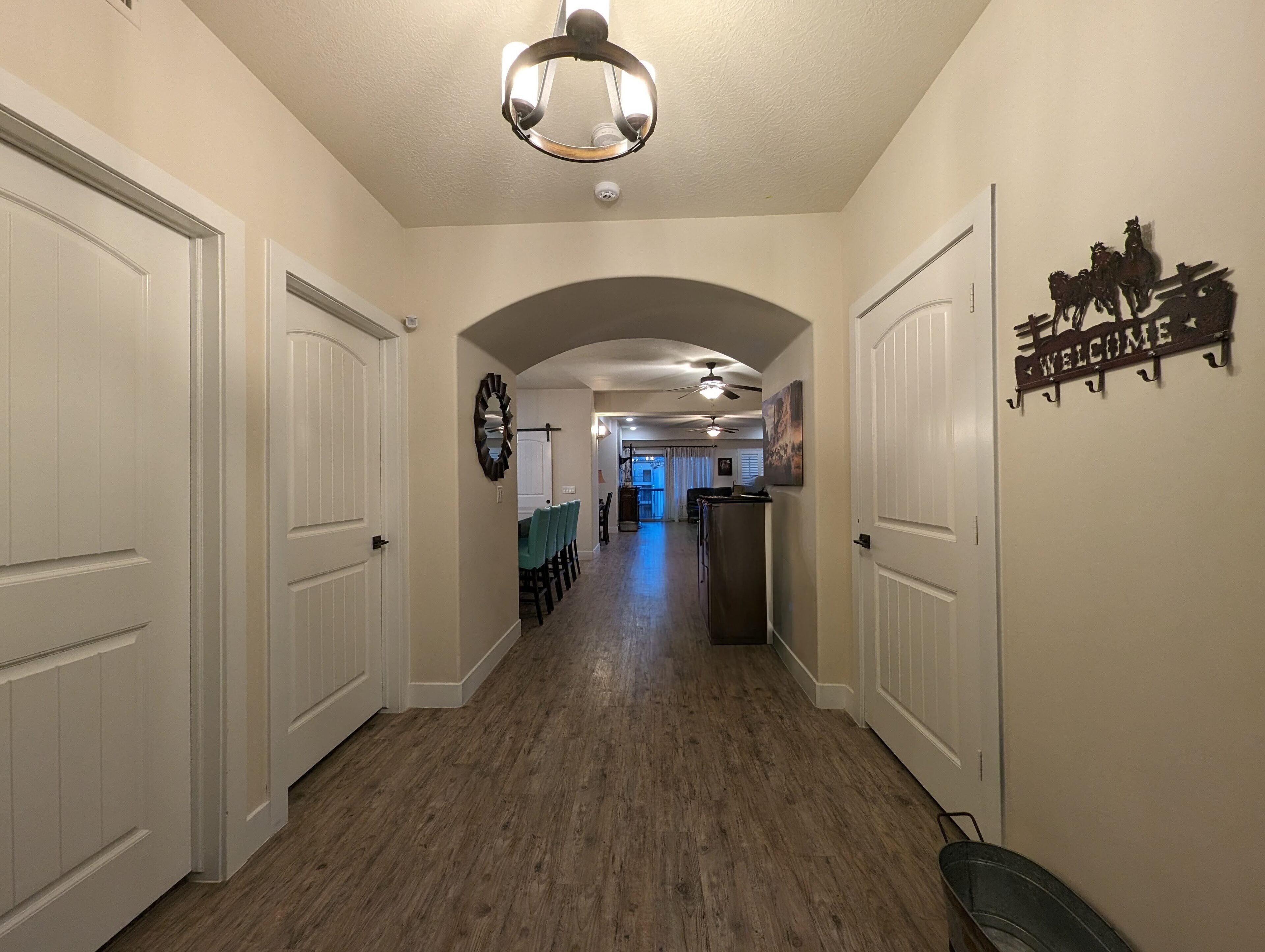 A hallway with white doors, a ceiling fan, and a welcome sign with horses.