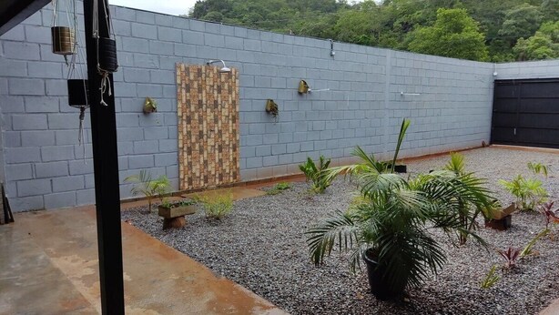 A rooftop garden with a grey brick wall, a wooden panel wall, and various potted plants. - Suíte maravilhosa Casa da Serra (Aurora do Tocantins)