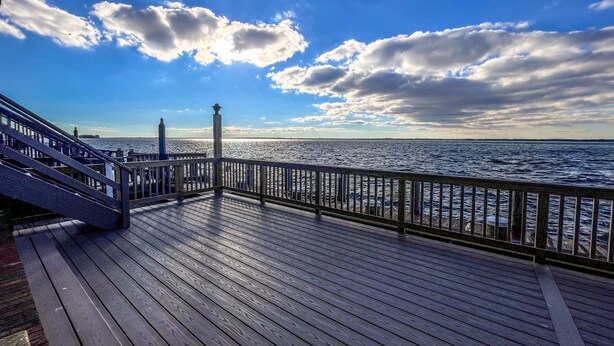A wooden deck with a railing overlooking a body of water. - Stunning 2BR/2BA Bayfront Retreat (Ocean City)