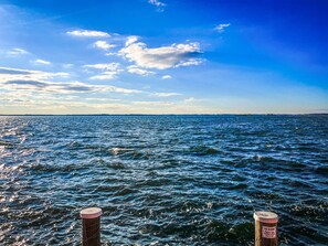 Une vue sur l’océan, avec un poteau en bois au premier plan et une pancarte fixée à celui-ci.
