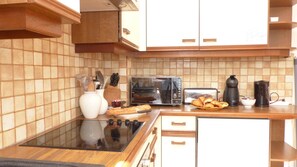 A kitchen with a tiled backsplash, a built-in oven, a toaster, and a coffee maker.
