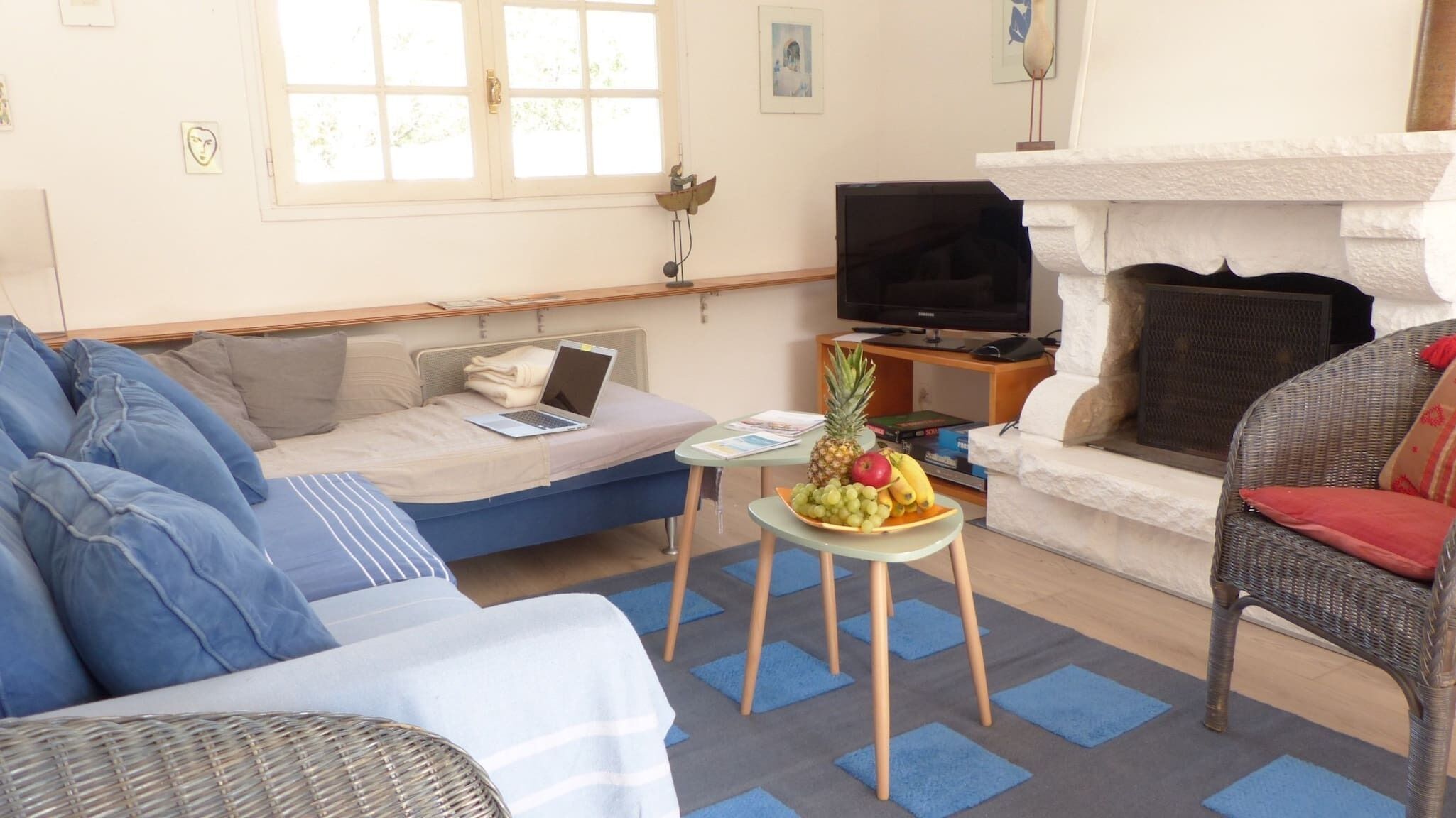 A living room with a sofa, a chair, a small table with fruit, a television, and a fireplace.
