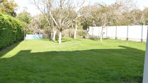 Ein Garten mit Gras, Bäumen und einem weißen Zaun.