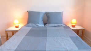 A bed with a blue and white checkered bedspread, flanked by two nightstands with lamps. - traditional Breton house (Belz)