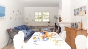 A dining area with a table set for breakfast, a sofa, and a fireplace.