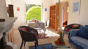 A cozy living room with a dining area, wicker furniture, and a bookshelf. - traditional Breton house (Belz)