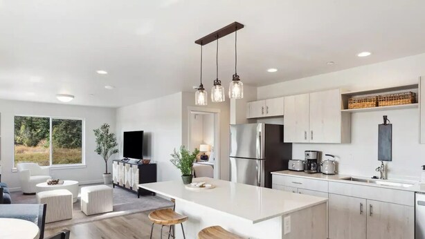 A modern kitchen with a central island, stainless steel appliances, and pendant lighting.