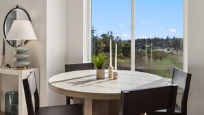 A dining area with a round table, four chairs, a lamp, and a view of the outdoors.