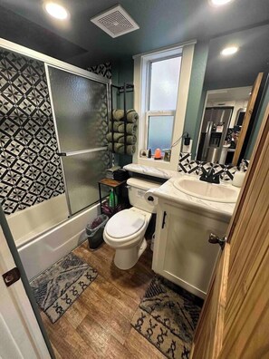 A compact bathroom with a toilet, sink, and shower. - Blueberry Farm Cottage | Hot Tub, Creek, Game Room (Mentone)