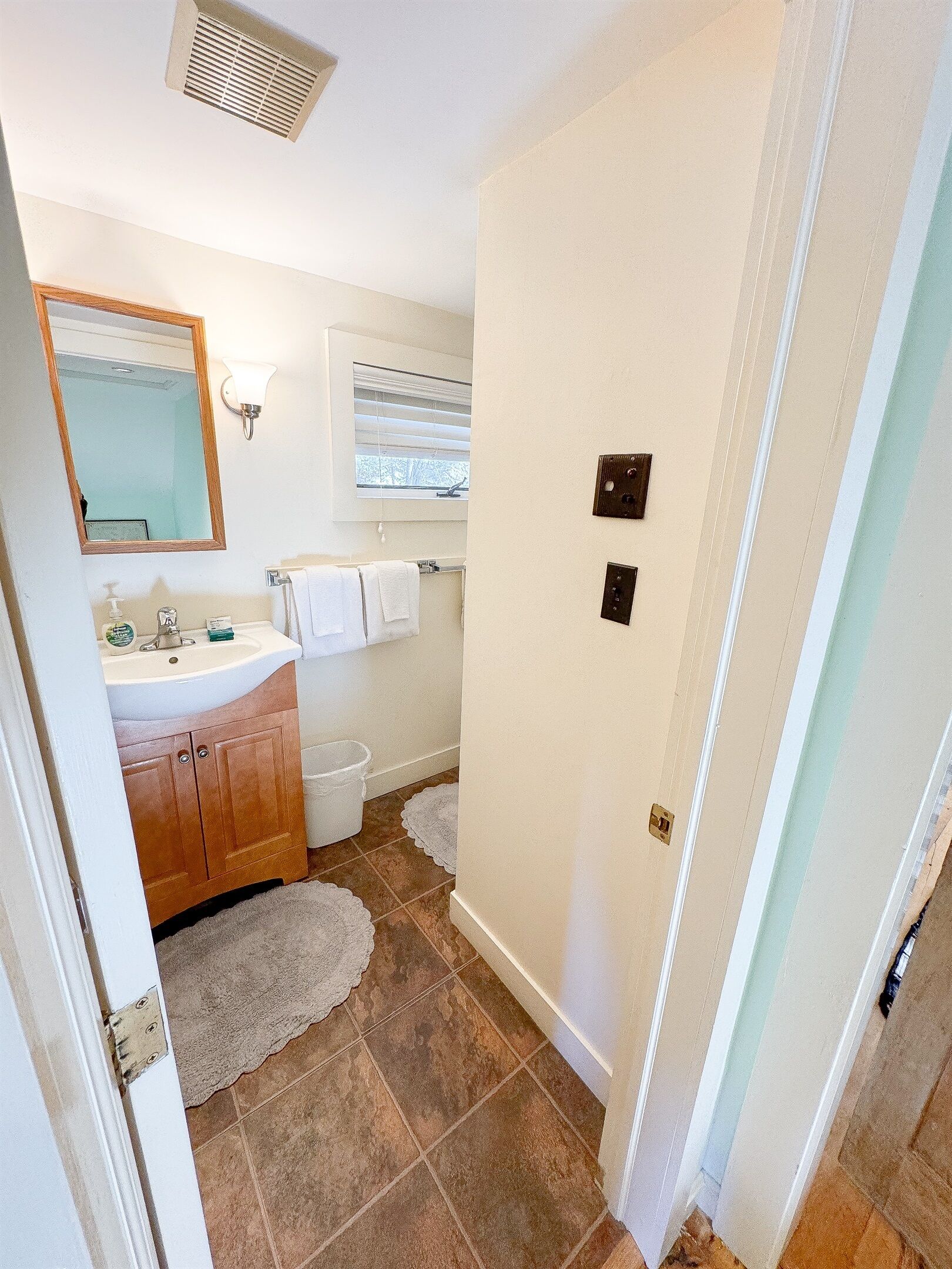 A bathroom with a sink, mirror, and window.