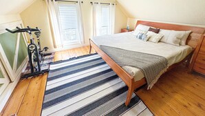 Una camera da letto con un letto, un comodino, una lampada, una finestra con tende e una bicicletta.