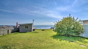 Une cour arrière verdoyante avec un petit abri de jardin, un arbre et une vue sur l’eau.