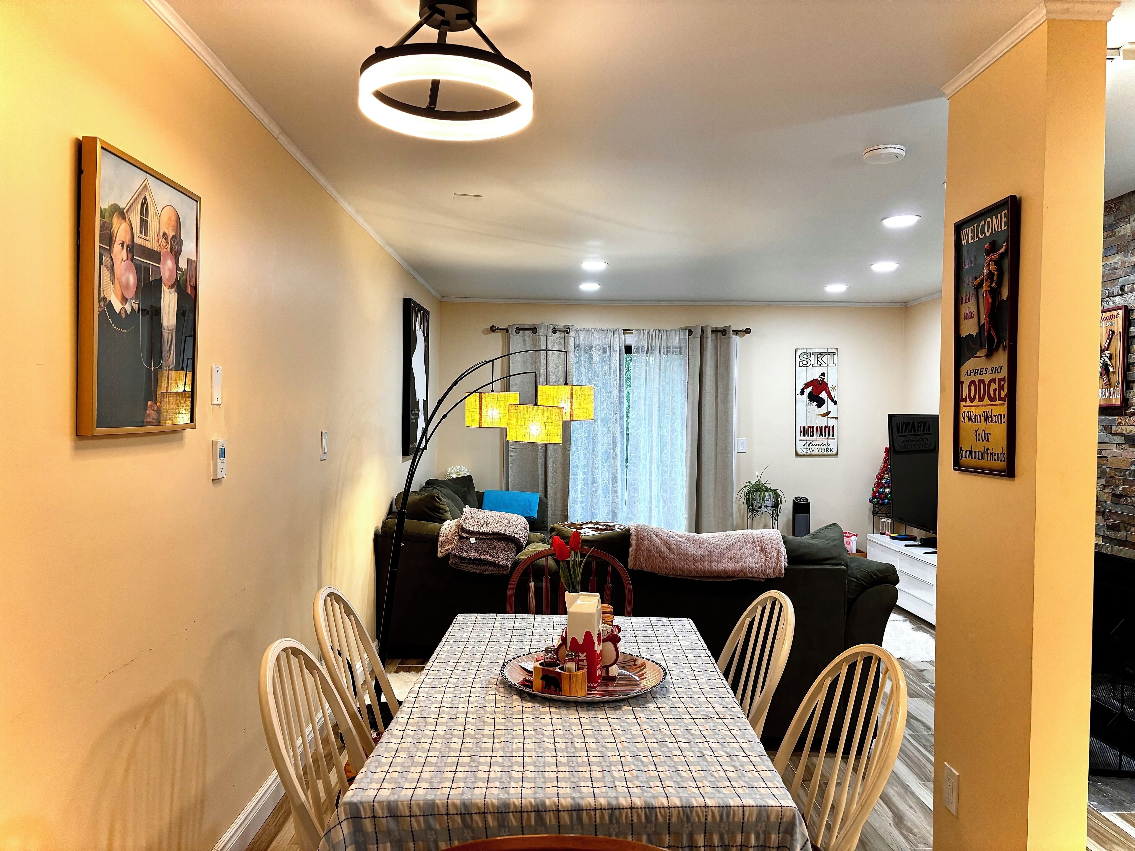 Un coin repas avec une table dressée pour quatre personnes, un canapé, une lampe et une affiche au mur.