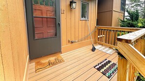 A wooden house with a dark door, a small window, and a porch with a doormat. - Cozy Ski On/Off Condo Located at Hunter Mountain (Hunter)