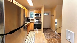 A kitchen with wooden cabinets, stainless steel appliances, and a patterned mat on the floor. - Cozy Ski On/Off Condo Located at Hunter Mountain (Hunter)