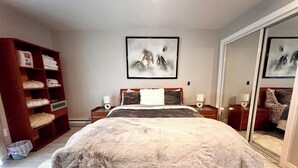 A bedroom with a large bed, a wardrobe, a bedside table with a lamp, and a mirror. - Cozy Ski On/Off Condo Located at Hunter Mountain (Hunter)