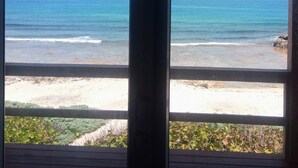 Uitzicht op een strand door een raam met houten kader.