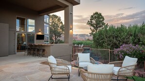 Eine Terrasse im Freien mit Korbmöbeln, einer Bar und Blick auf die umliegende Landschaft.