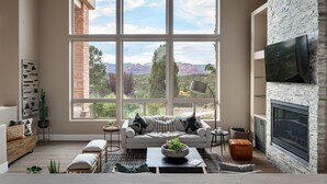 Ein Wohnzimmer mit großem Fenster, Kamin und Fernseher.