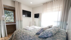 Un dormitorio con cama, televisor y ventana con cortinas.