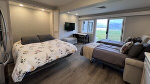 A bedroom with a large bed, a smaller bed, a desk, and a TV. - Lakefront Studio Condo~Step into the Lake at Spader Bay (Chelan)