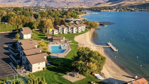 A coastal hotel with a swimming pool, beach access, and a view of the lake and mountains. - Lakefront Studio Condo~Step into the Lake at Spader Bay (Chelan)