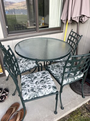 A round glass table with four chairs, each with a floral-patterned cushion.