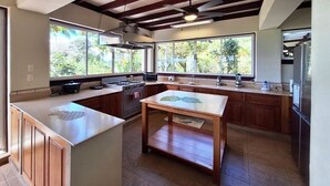 Uma cozinha espaçosa com ilha central, janelas amplas e ventilador de teto.