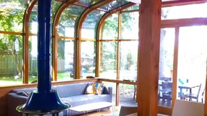 A room with a large glass window, a blue heater, a sofa, and a dining table. - Victorian Modern, on the Mississippi River (Minneapolis)