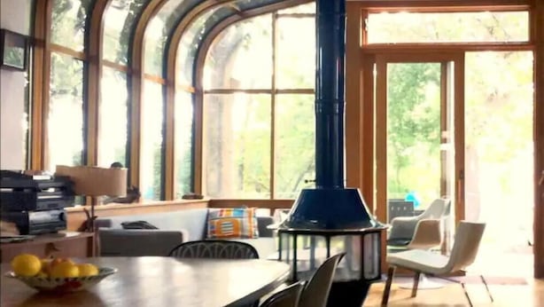 A dining area with a large table, chairs, and a bowl of lemons. There is a blue lantern-style light fixture and a window with a view of trees. - Victorian Modern, on the Mississippi River (Minneapolis)