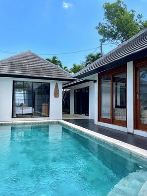 Uma casa moderna com piscina, janelas amplas e um deck de madeira.