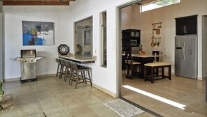 A modern kitchen with a built-in oven, a dining area with a table and chairs, and a large refrigerator. - 3BD Private Villa Konka with pool  (Cóbano)