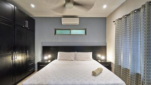 A modern hotel room with a large bed, dark wooden wardrobe, and a patterned curtain. - 3BD Private Villa Konka with pool  (Cóbano)