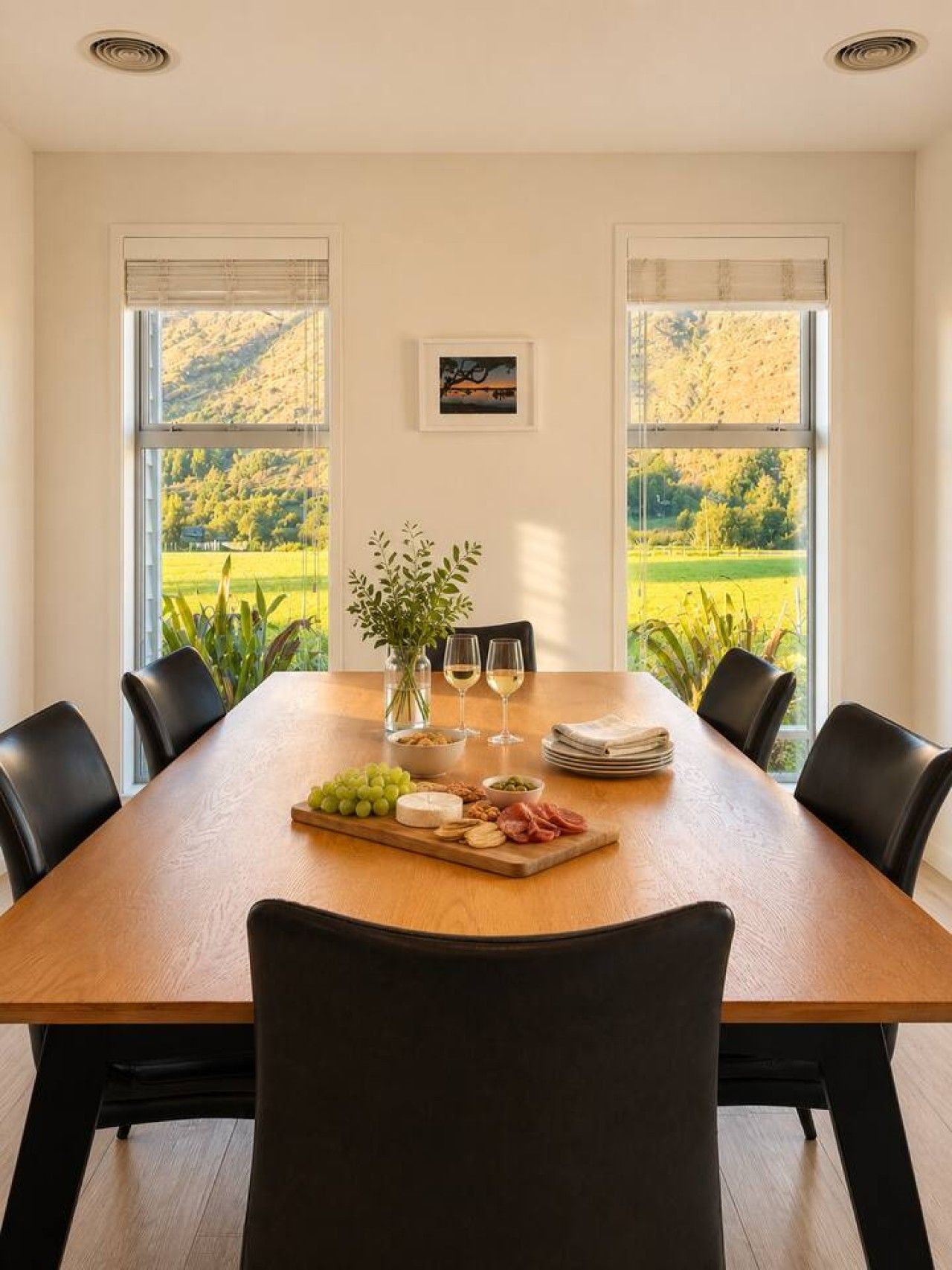 Une table à manger donnant sur un paysage verdoyant grâce à de grandes fenêtres.