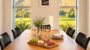 Un tavolo da pranzo con vista su un paesaggio verdeggiante attraverso ampie finestre.