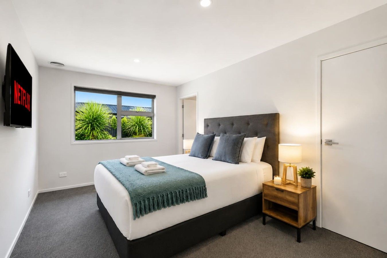 Une chambre d’hôtel moderne avec un grand lit, une table de chevet avec une lampe et un téléviseur fixé au mur.